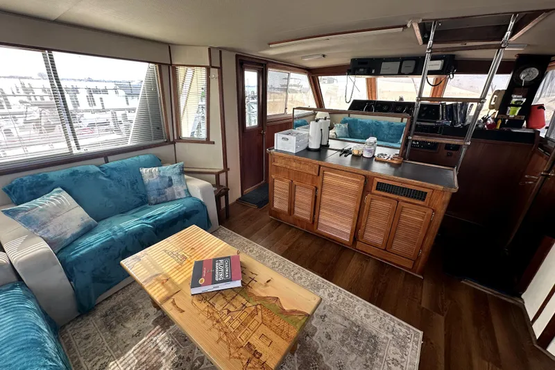 Slide: The Image of 1985 Chris-Craft 500 Constellation interior with cozy seating, wooden cabinetry, and nautical decor. - 9