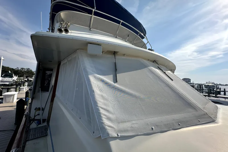 Slide: The Image of 1985 Chris-Craft 500 Constellation yacht docked, featuring covered windows and blue sky background. - 99