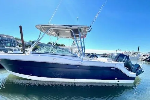Slide: The Image of 2014 Robalo R247 Dual Console boat docked in marina under clear blue sky. - 0