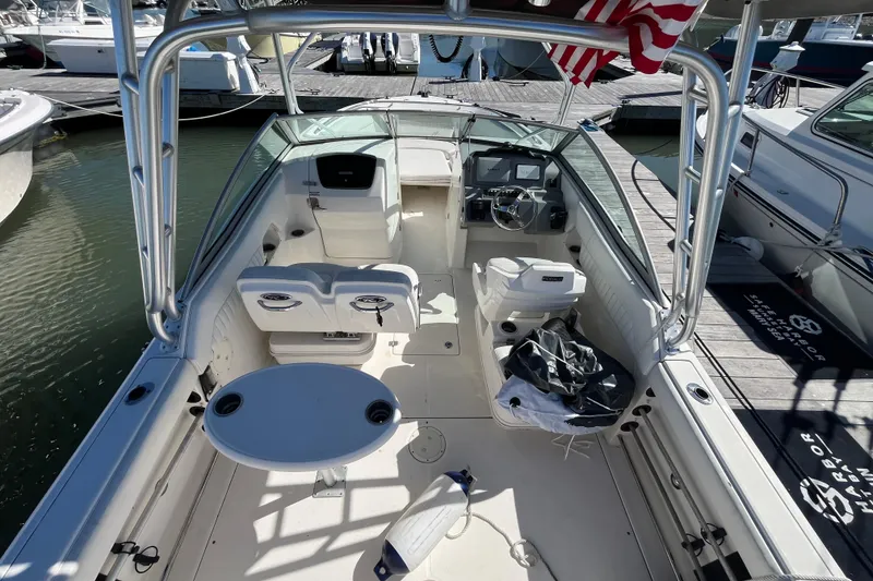 Slide: The Image of 2014 Robalo R247 Dual Console boat docked, featuring spacious seating and helm area. - 12