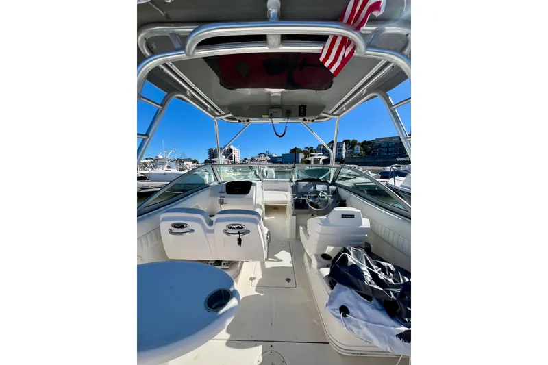 Slide: The Image of 2014 Robalo R247 Dual Console boat interior with helm, seating, and canopy in marina setting. - 15