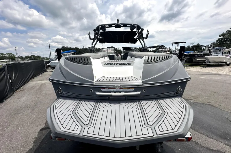 Slide: The Image of 2016 Nautique Super Air Nautique G25 Coastal Edition boat, rear view, docked under cloudy sky. - 14