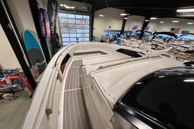 Slide: The Image of 2023 Sea Ray Sundancer 370 Outboard displayed in a showroom with surfboards and accessories. - 31