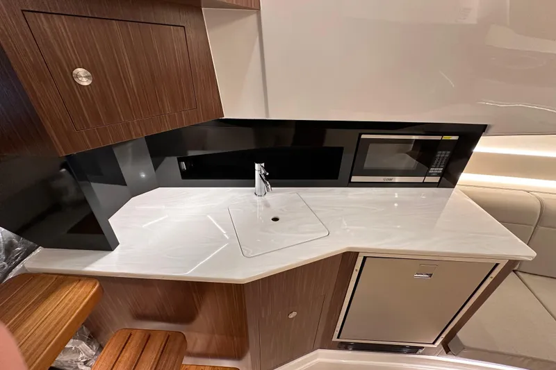 Slide: The Image of 2023 Sea Ray Sundancer 370 Outboard interior kitchen with sink, microwave, and fridge. - 37