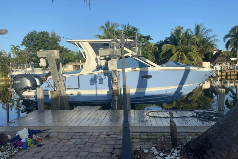 Slide: The Image of 2022 Chaparral 280 OSX boat docked by a tropical waterfront. - 1