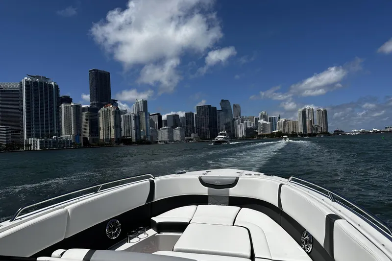 Slide: The Image of Chaparral 280 OSX 2022 boat cruising near city skyline under blue sky. - 7