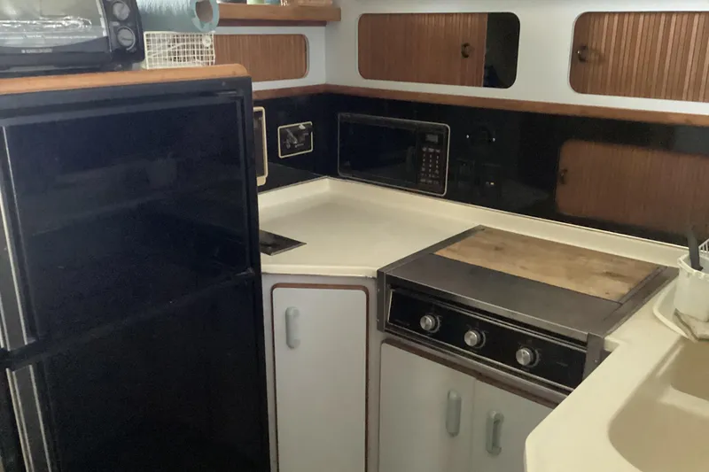 Slide: The Image of 1989 Sea Ray 380 Aft Cabin kitchen with stove, microwave, and refrigerator. - 16