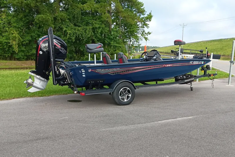 Slide: The Image of 2021 Ranger RT188P boat on trailer, parked on road with green trees in background. - 2