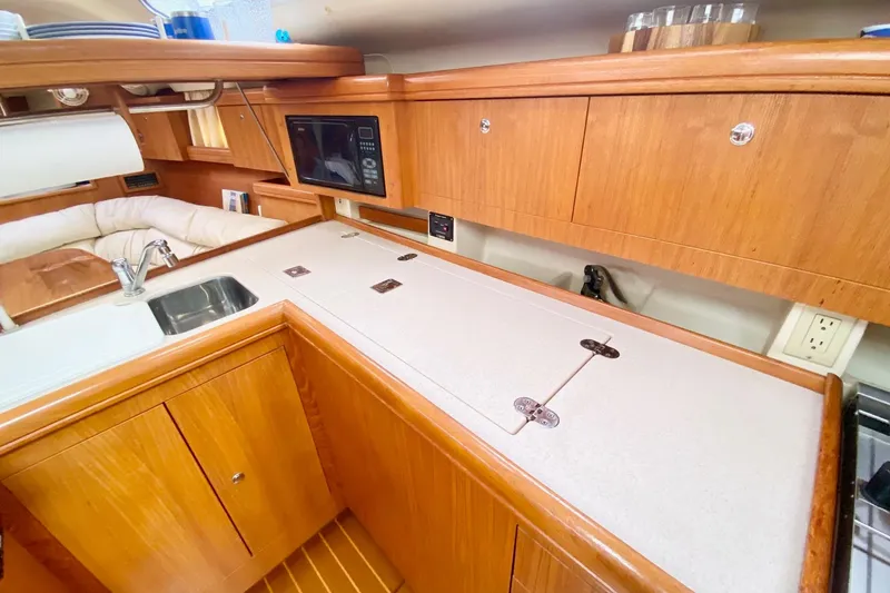 Slide: The Image of 2003 Hunter 386 yacht interior with wooden cabinetry, sink, and microwave in the galley area. - 26