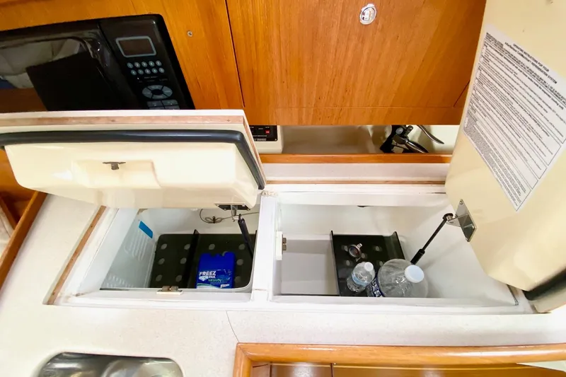 Slide: The Image of 2003 Hunter 386 yacht kitchen with open storage compartments and microwave. - 27