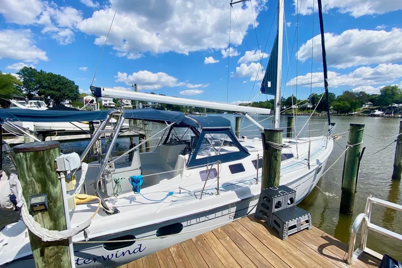 Slide: The Image of 2003 Hunter 386 sailboat docked under a bright blue sky with fluffy clouds. - 41