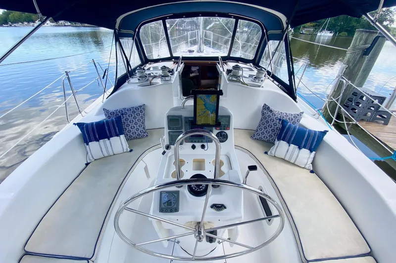 Slide: The Image of Cockpit of 2003 Hunter 386 sailboat with navigation equipment and cushions, docked by calm water. - 54