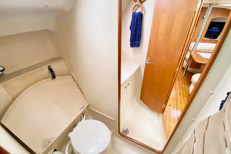 Slide: The Image of 2003 Hunter 386 yacht bathroom with toilet, mirror, and wooden door. - 7