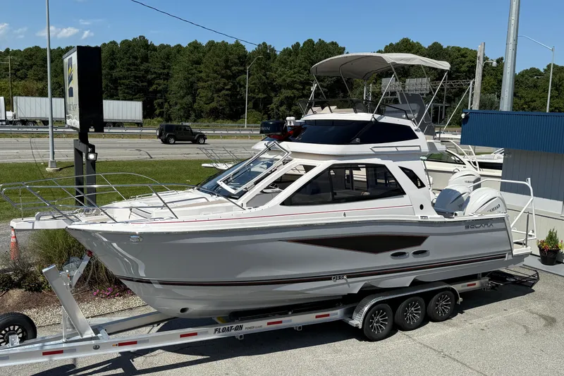 The Image of 2026 Solara S-310 SB boat on trailer, parked near highway with trees in background. - 1
