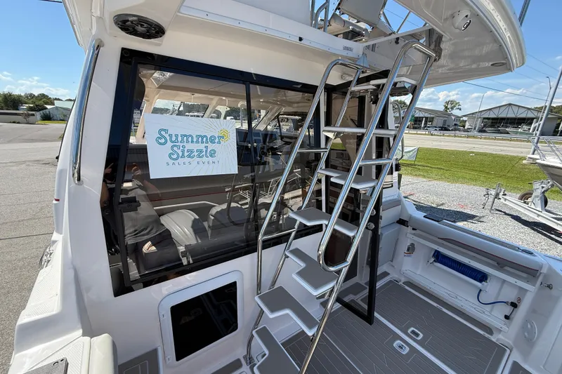 Slide: The Image of 2026 Solara S-310 SB boat with ladder, "Summer Sizzle" sales event sign, docked outdoors. - 10