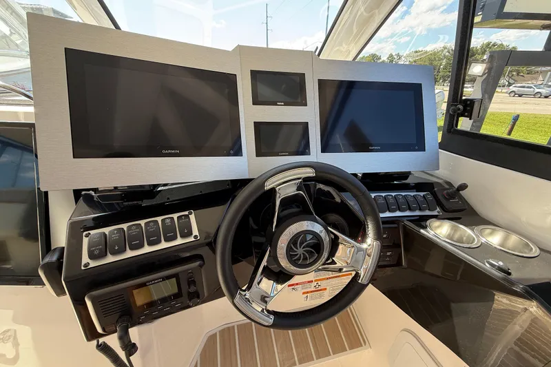 Slide: The Image of 2026 Solara S-310 SB boat dashboard with multiple Garmin screens and steering wheel. - 18