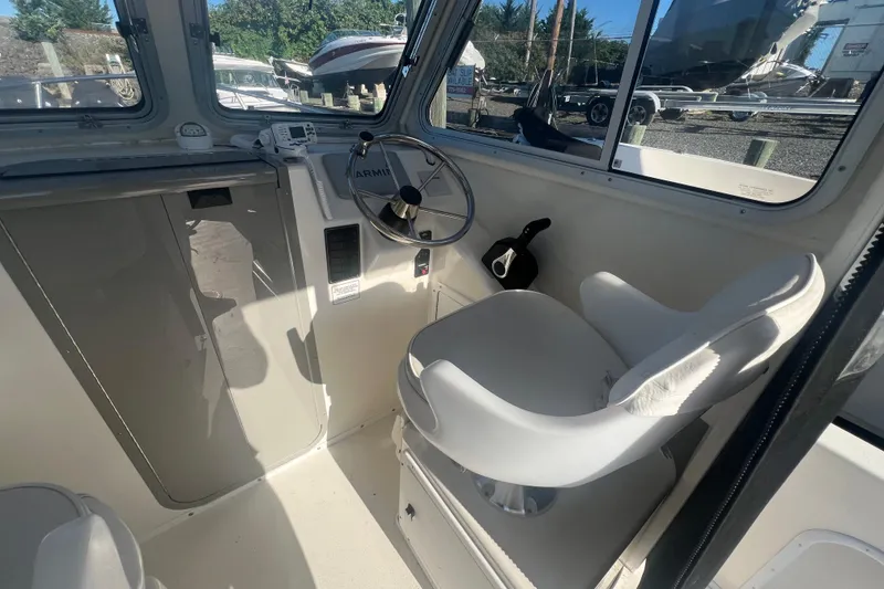 Slide: The Image of Interior of 2022 May-Craft 2300 Pilot House boat with steering wheel and seat. - 5