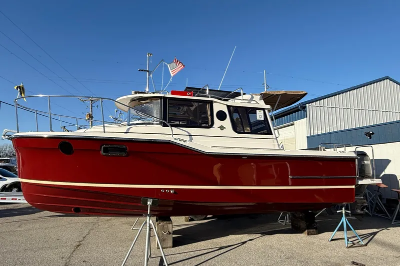 The Image of 2026 Ranger Tugs R-23 boat in vibrant red, displayed outdoors on stands. - 1