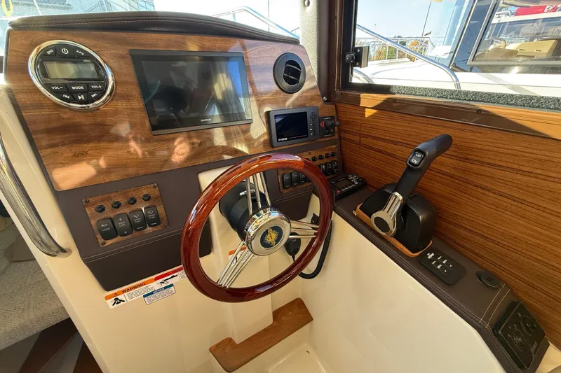 Slide: The Image of 2026 Ranger Tugs R-23 helm with wood accents, steering wheel, and control panel. - 12