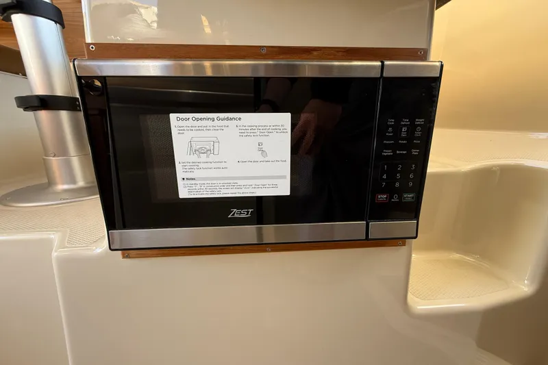 Slide: The Image of Microwave in 2026 Ranger Tugs R-23 boat interior, featuring Zest brand and door opening guidance. - 14