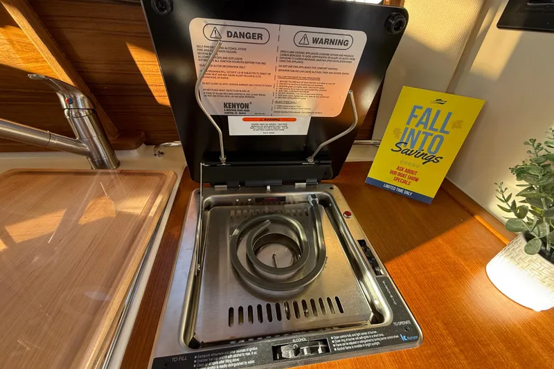 Slide: The Image of Kenyon stove in 2026 Ranger Tugs R-23 boat kitchen, with safety warnings and promotional flyer. - 18