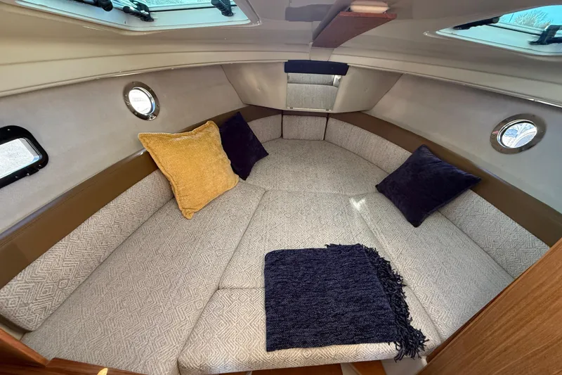 Slide: The Image of 2026 Ranger Tugs R-23 cabin interior with cozy seating and decorative pillows. - 19