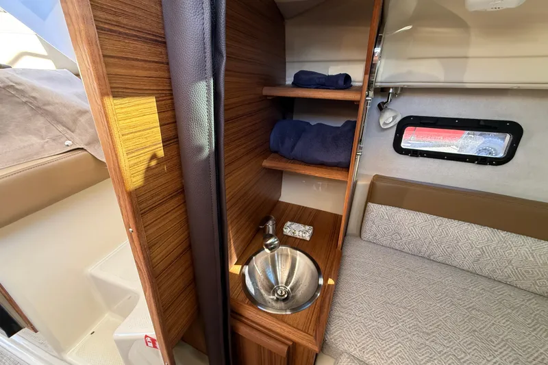 Slide: The Image of 2026 Ranger Tugs R-23 interior with sink, shelves, and seating area. - 20