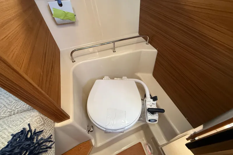 Slide: The Image of 2026 Ranger Tugs R-23 boat bathroom with compact toilet and wooden paneling. - 22