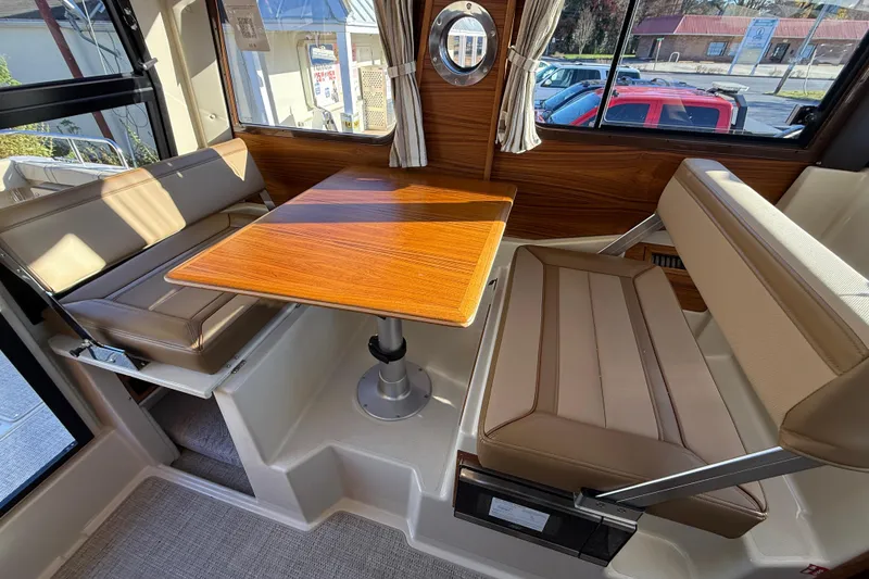 Slide: The Image of 2026 Ranger Tugs R-23 interior with wood table and beige seating. - 9