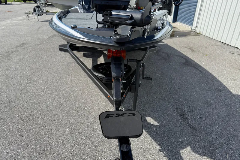 Slide: The Image of 2026 Skeeter FXR21 FLEX boat on trailer, parked outdoors near a metal building. - 11