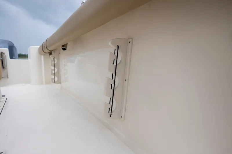 Slide: The Image of 2017 Key West 244 Center Console boat interior detail, featuring rod holders and cushioned side. - 20
