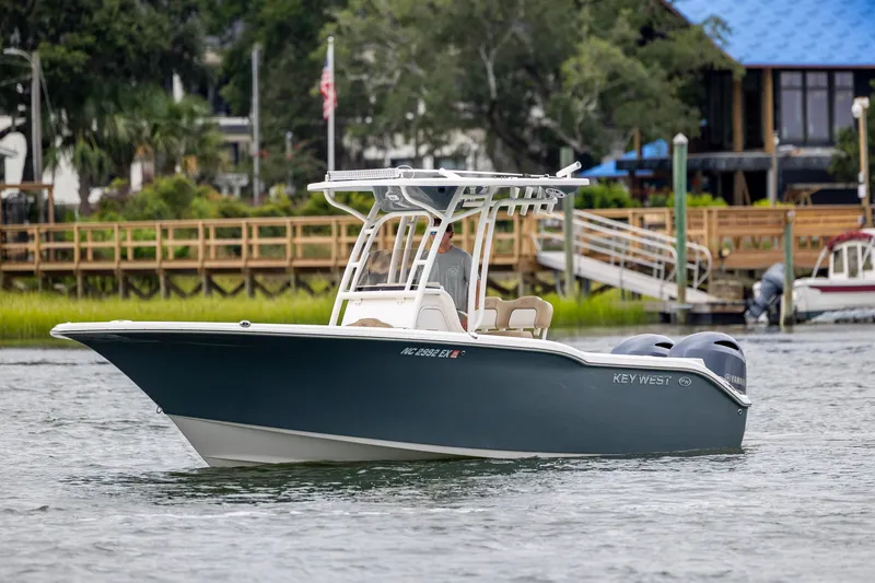 Slide: The Image of 2017 Key West 244 Center Console boat cruising on a calm waterway near a wooden dock. - 3