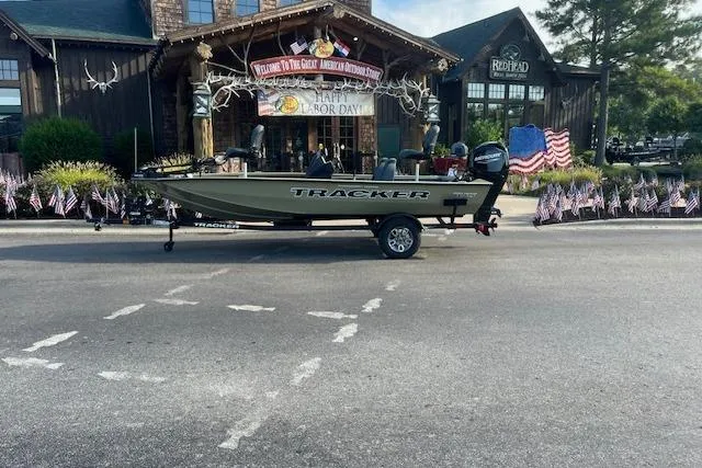 Slide: The Image of 2026 Tracker Pro Team 175 boat on trailer, outdoor store backdrop, Labor Day banner. - 2