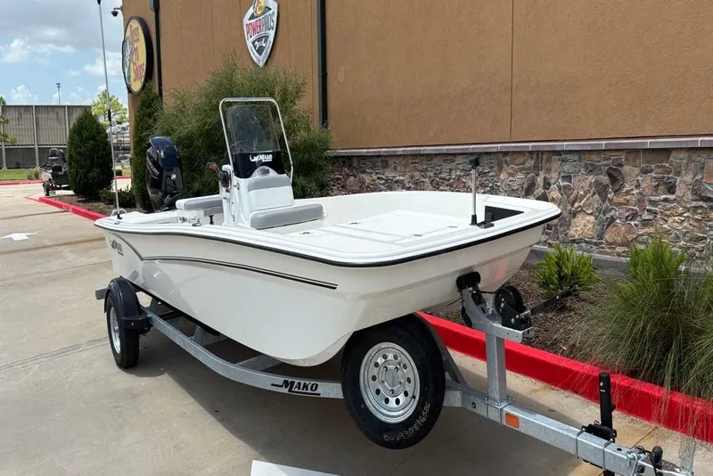 Slide: The Image of 2026 Mako Pro Skiff 17 CC boat on trailer, parked outside a building. - 3