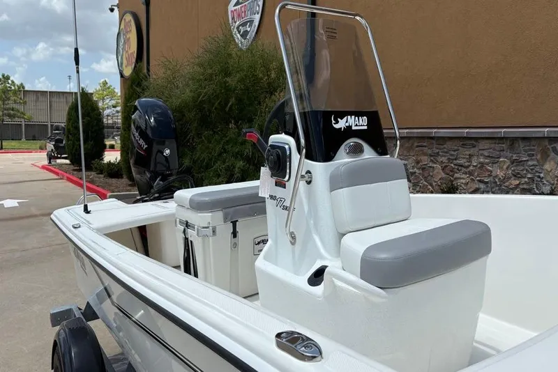 Slide: The Image of 2026 Mako Pro Skiff 17 CC boat with console and seating, parked outdoors. - 4