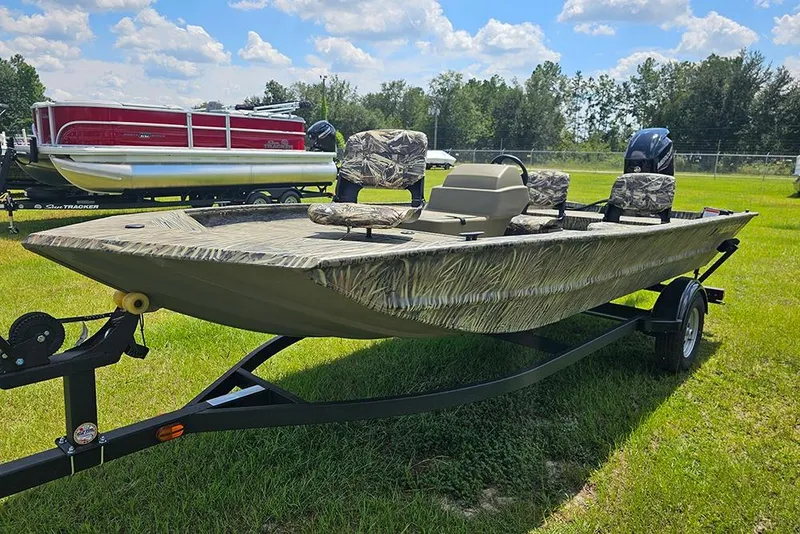 Slide: The Image of 2026 Tracker Grizzly 1754 SC boat on trailer, camo seats, grassy field background. - 5