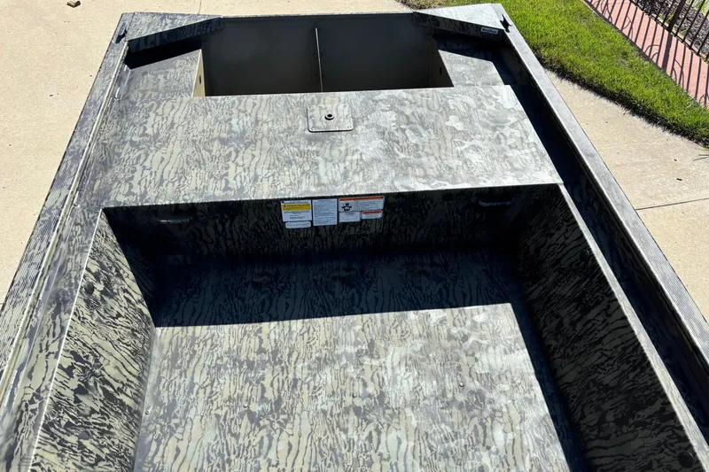 Slide: The Image of 2026 Tracker Grizzly 1648 Utility boat with camouflage interior design, parked on concrete. - 4