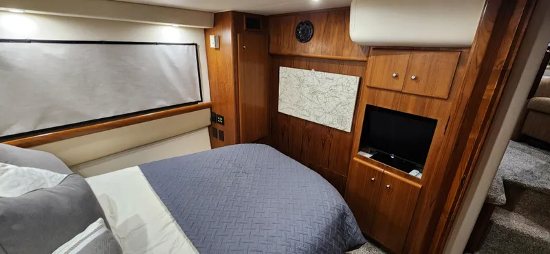Slide: The Image of 1998 Carver 355 Aft Cabin Motor Yacht bedroom with wood paneling, bed, and small TV. - 26