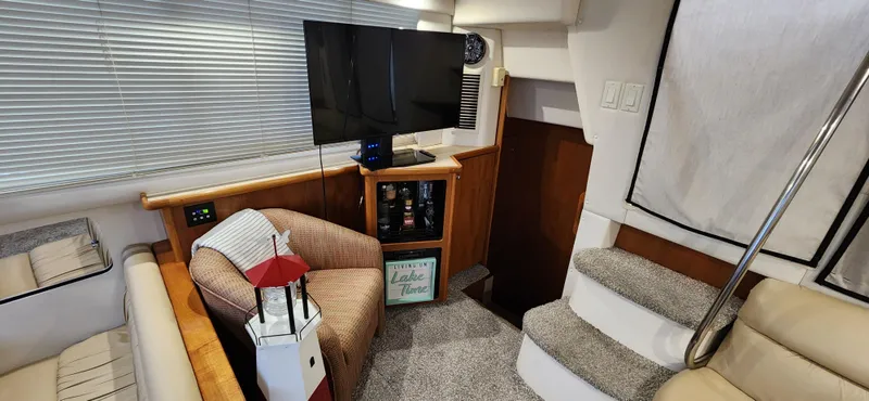 Slide: The Image of 1998 Carver 355 Aft Cabin Motor Yacht interior with cozy seating, TV, and stairs. - 16