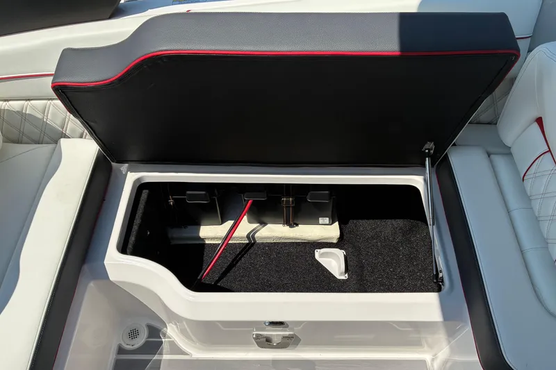 Slide: The Image of 2022 Regal LX2 boat storage compartment with open lid, featuring black and red trim. - 11