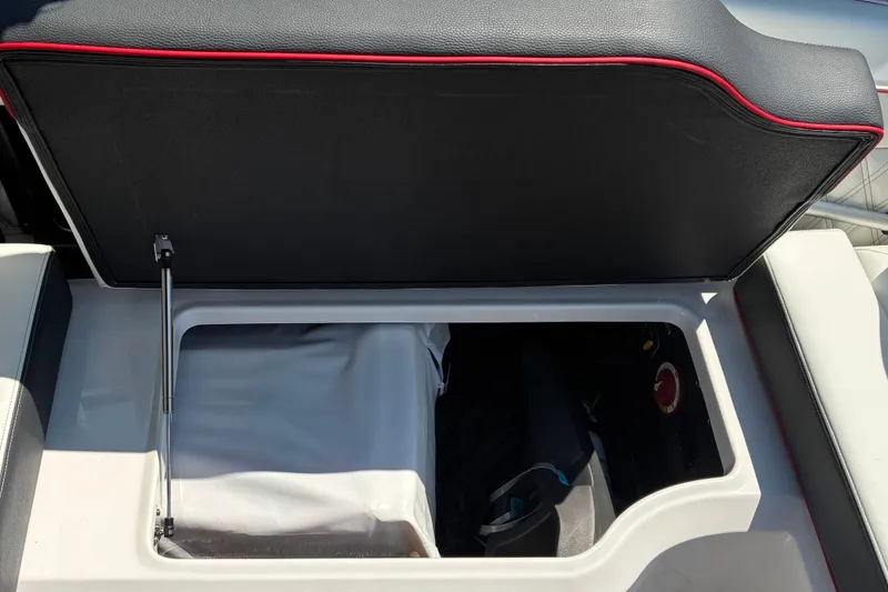 Slide: The Image of 2022 Regal LX2 boat storage compartment with open lid, featuring black and red trim. - 13