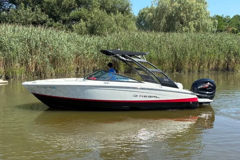 Slide: The Image of 2022 Regal LX2 boat on calm water, surrounded by lush greenery. - 3