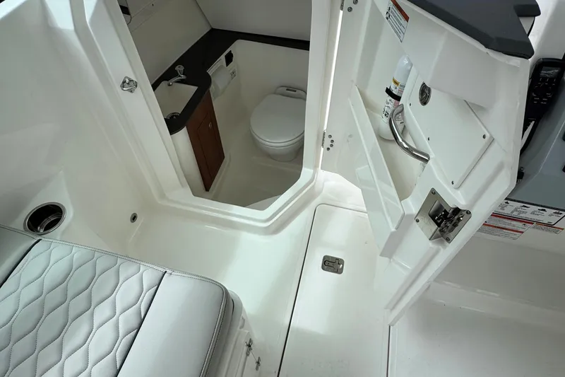 Slide: The Image of 2026 Pursuit DC 266 Dual Console boat interior with compact bathroom and seating. - 16