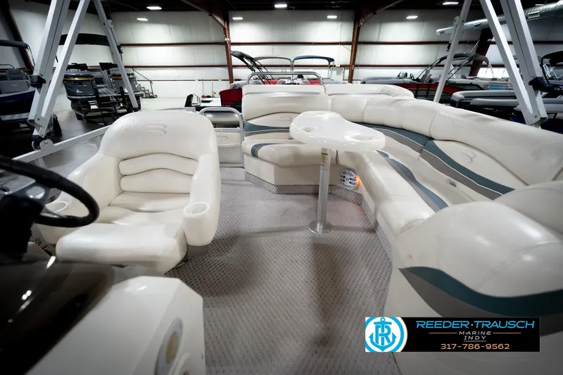 Slide: The Image of 2006 Bennington 2250RL pontoon boat interior with plush seating and table in showroom. - 16