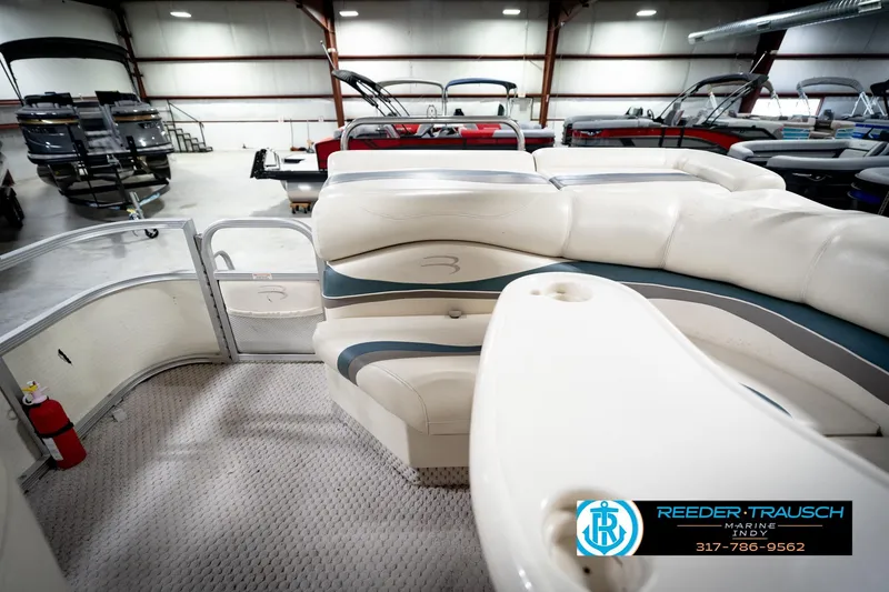 Slide: The Image of 2006 Bennington 2250RL pontoon boat interior with plush seating in a showroom. - 17