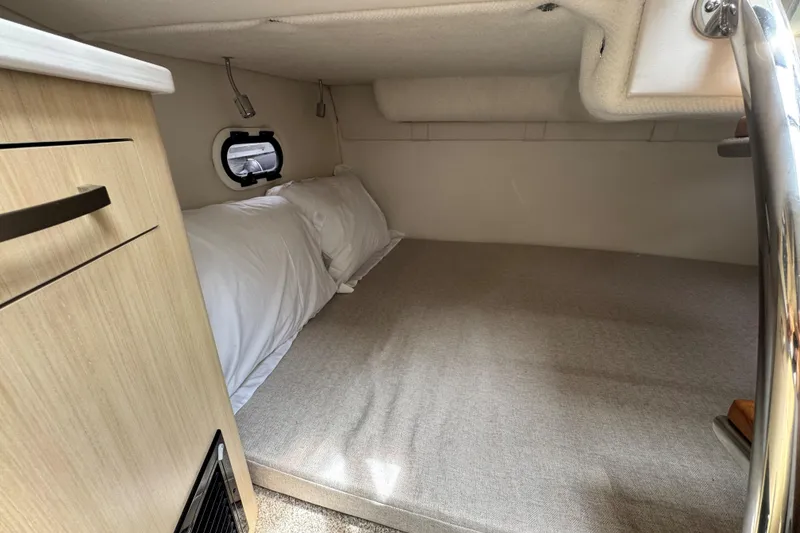 Slide: The Image of 2026 Regal 26 XO cabin interior with bed, porthole, and wooden cabinetry. - 28