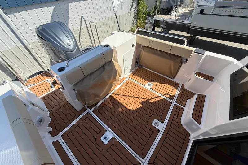 Slide: The Image of 2026 Ranger Tugs R-25 boat interior with teak flooring and cushioned seating. - 14