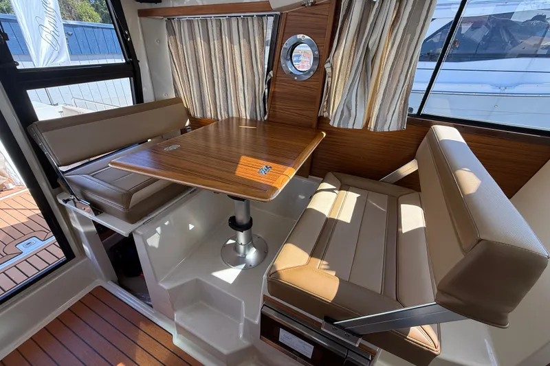 Slide: The Image of 2026 Ranger Tugs R-25 interior with dining area, wood table, and beige seating. - 15