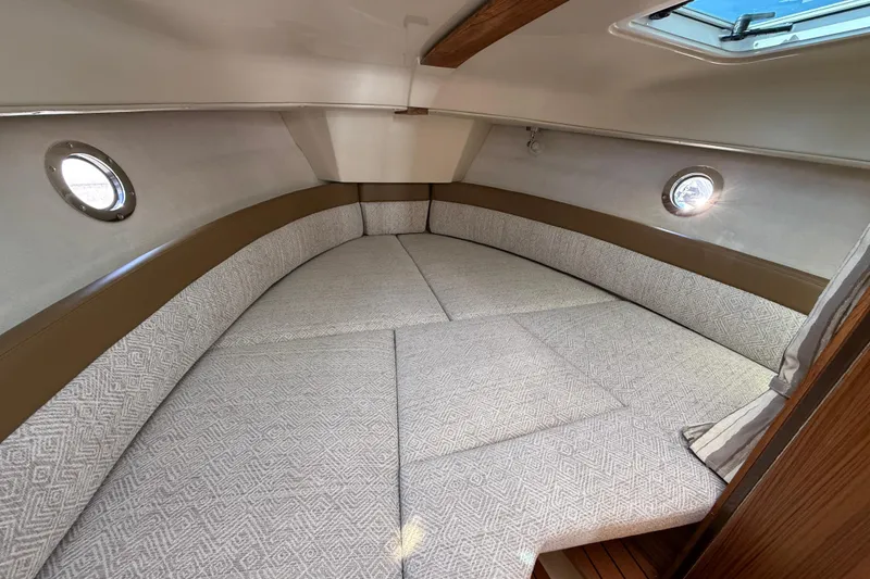 Slide: The Image of 2026 Ranger Tugs R-25 cabin interior with cozy seating and porthole windows. - 18