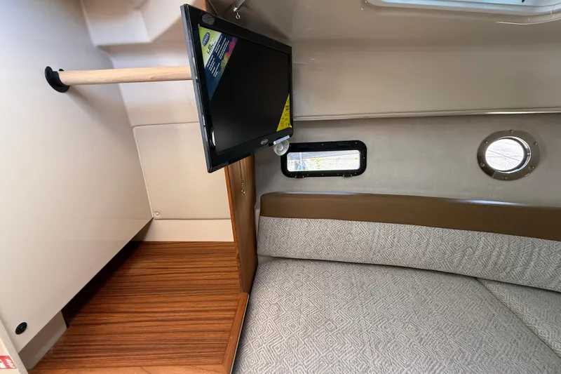 Slide: The Image of 2026 Ranger Tugs R-25 cabin interior with TV, cozy seating, and porthole window. - 21